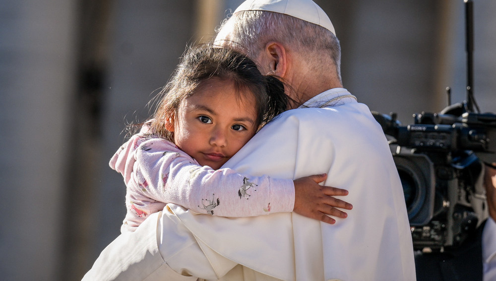 Papst Leo XIV. hat ein Mädchen auf dem Arm, das ihn umarmt bei der Generalaudienz am 8. Oktober 2025 auf dem Petersplatz im Vatikan