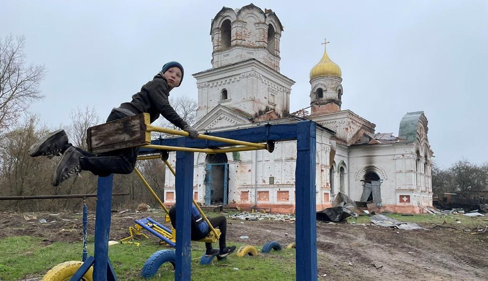 Ukrainische Kinder spielen vor Kriegsruine