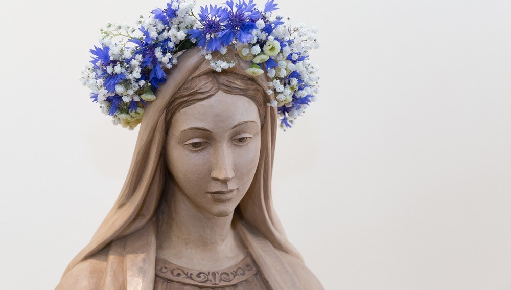 Geschnitzte Statue der Jungfrau Maria mit Blumenkranz