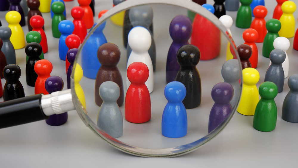 Spielfiguren mit einer Gruppe, die durch eine Lupe betrachtet wird
